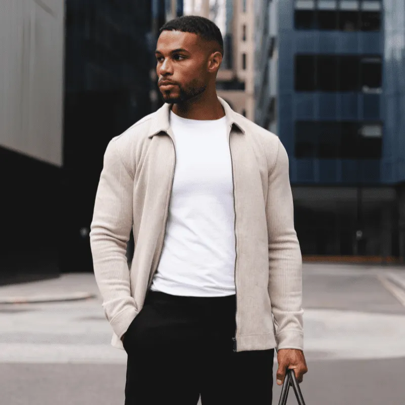Man in a stone overshirt and white t-shirt on a city street