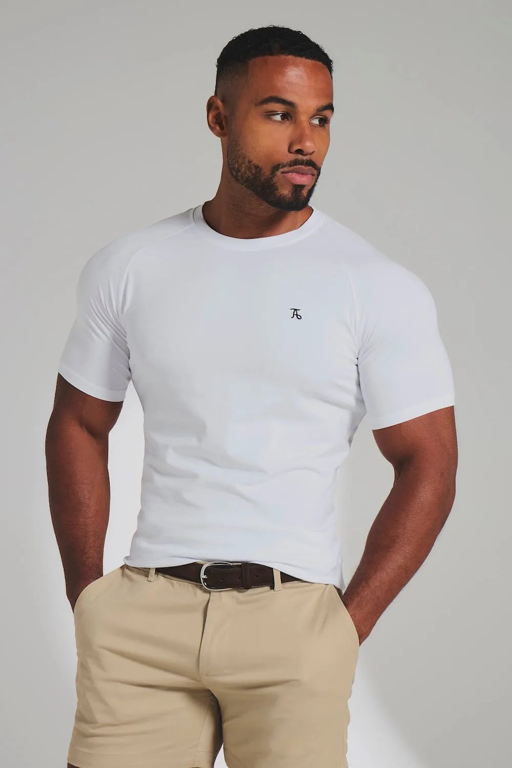 Athlete in a white raglan t-shirt and stone shorts, hands in pockets