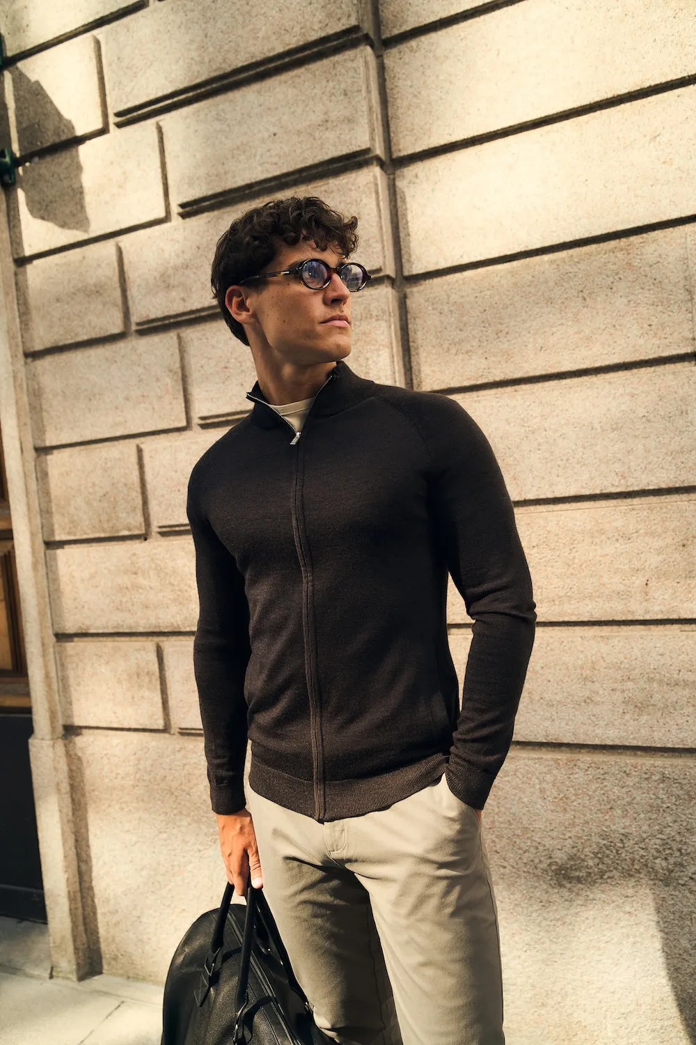 Man in a black long sleeve shirt with a leather bag on a city street