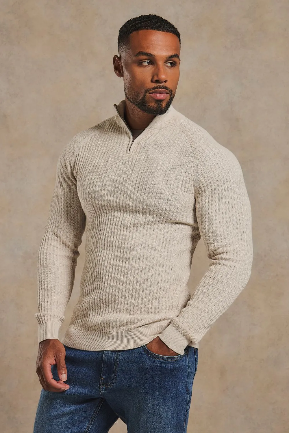 Model in a textured knitted half zip sweater in alabaster and jeans