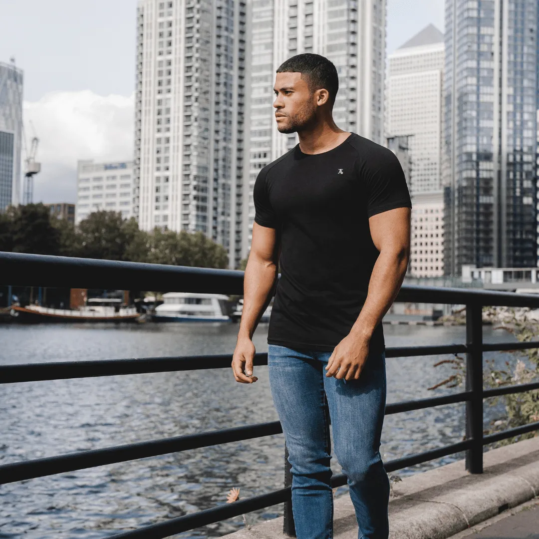Man in a black t-shirt and jeans by a city river